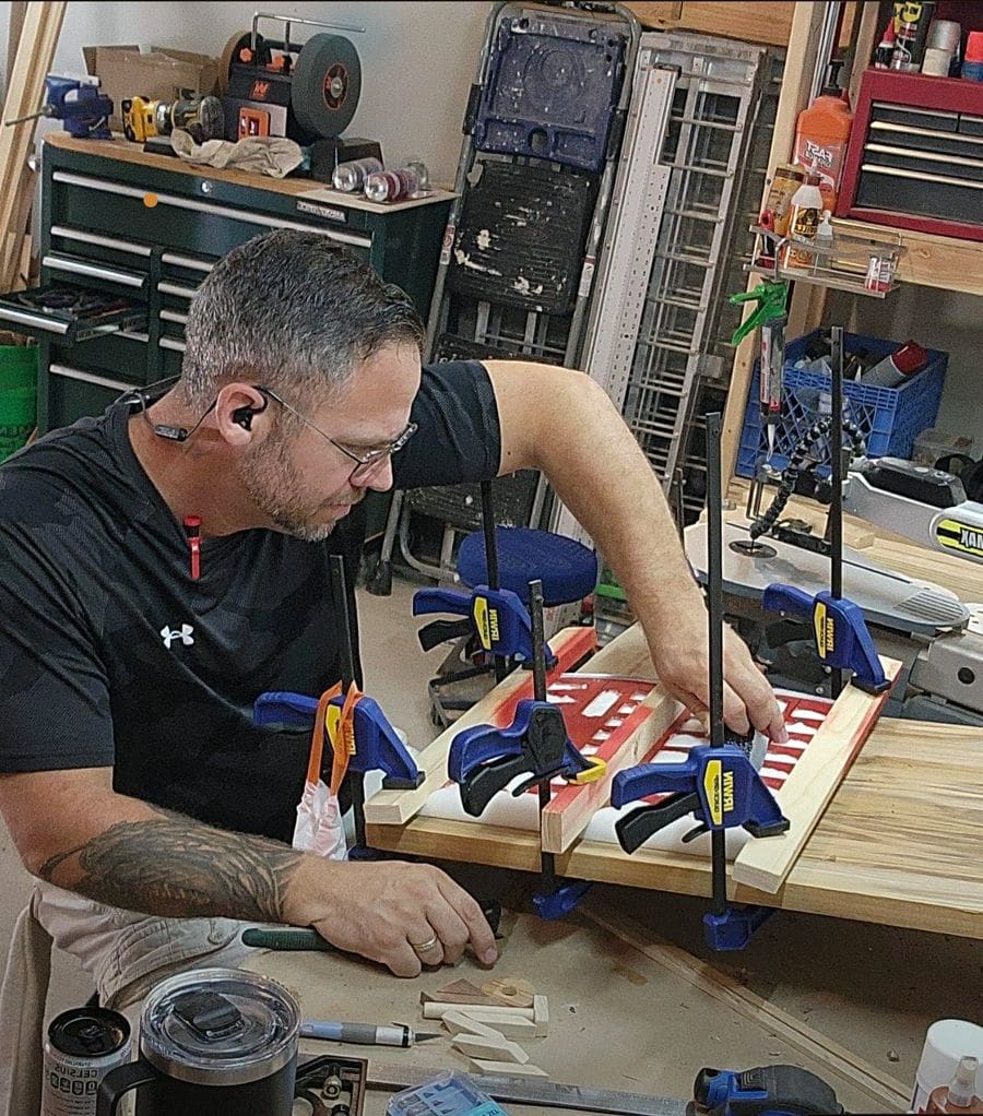 The owner at the workbench, squaring up a glue-up with clamps