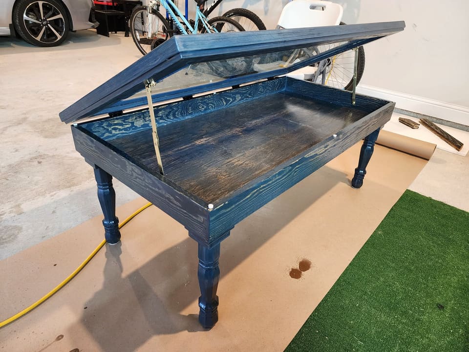 The blue display table with its glass top propped open