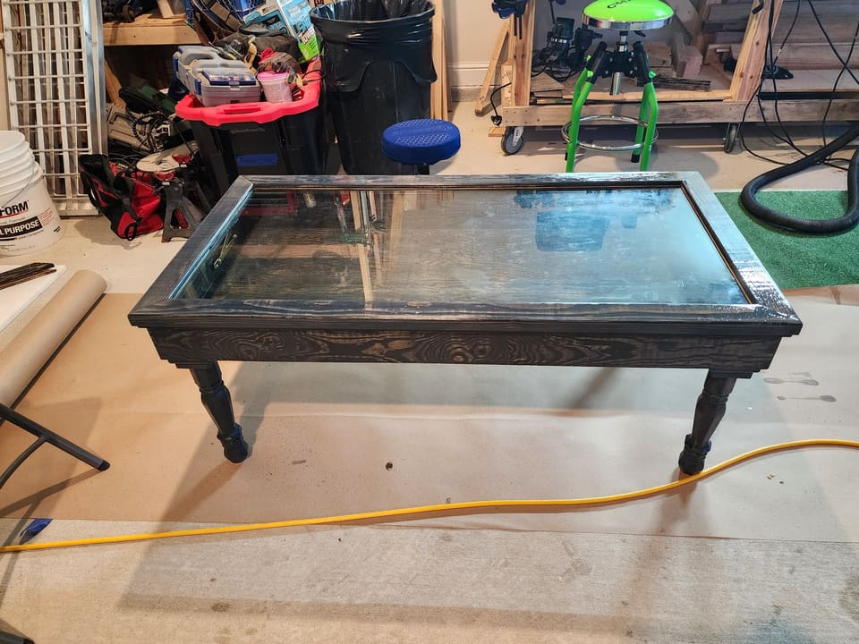 Distressed dark shadow-box coffee table with a glass top in the workshop