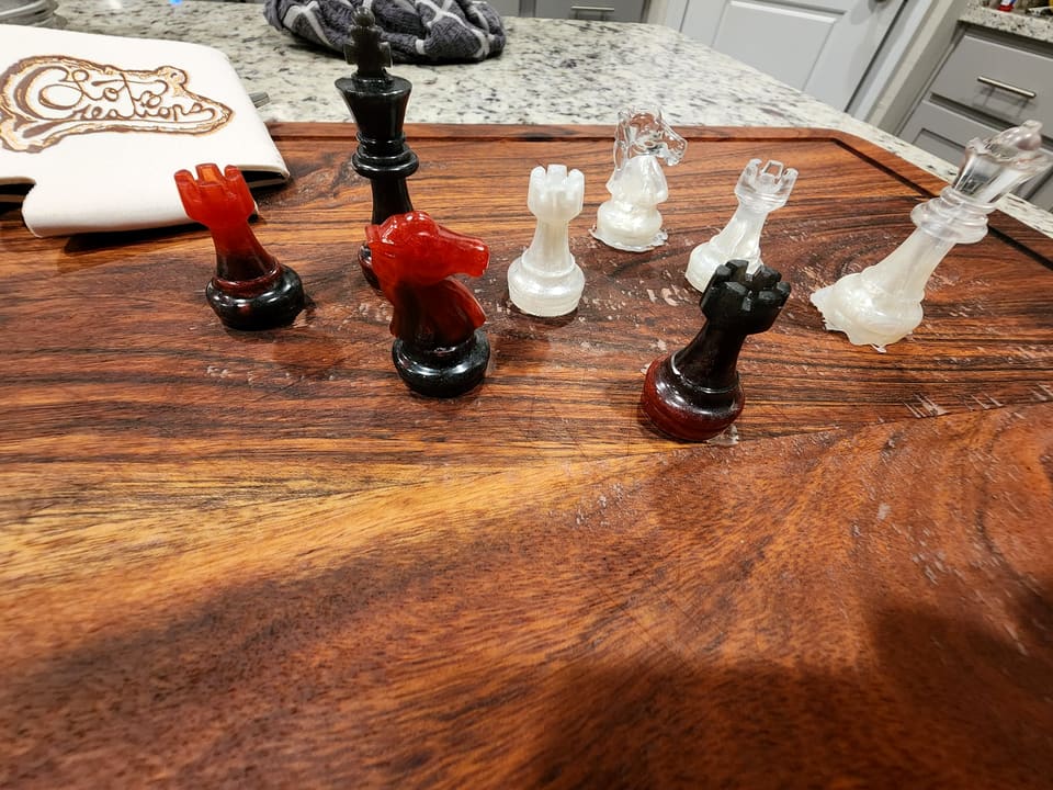 Cast resin chess pieces in red and clear on a wood surface