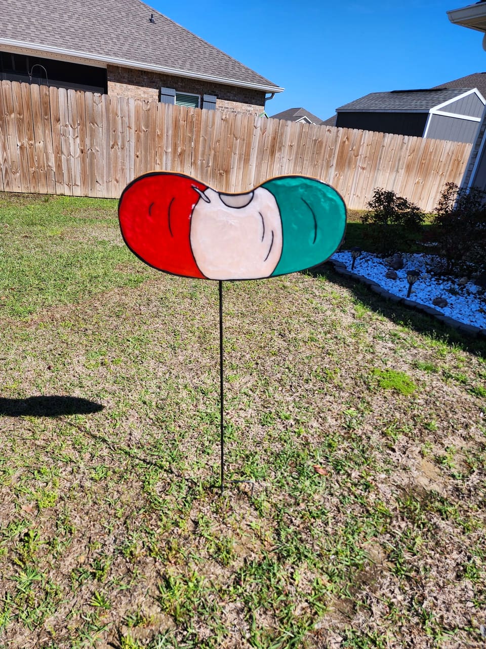 Large painted watermelon-slice garden stake standing in a lawn