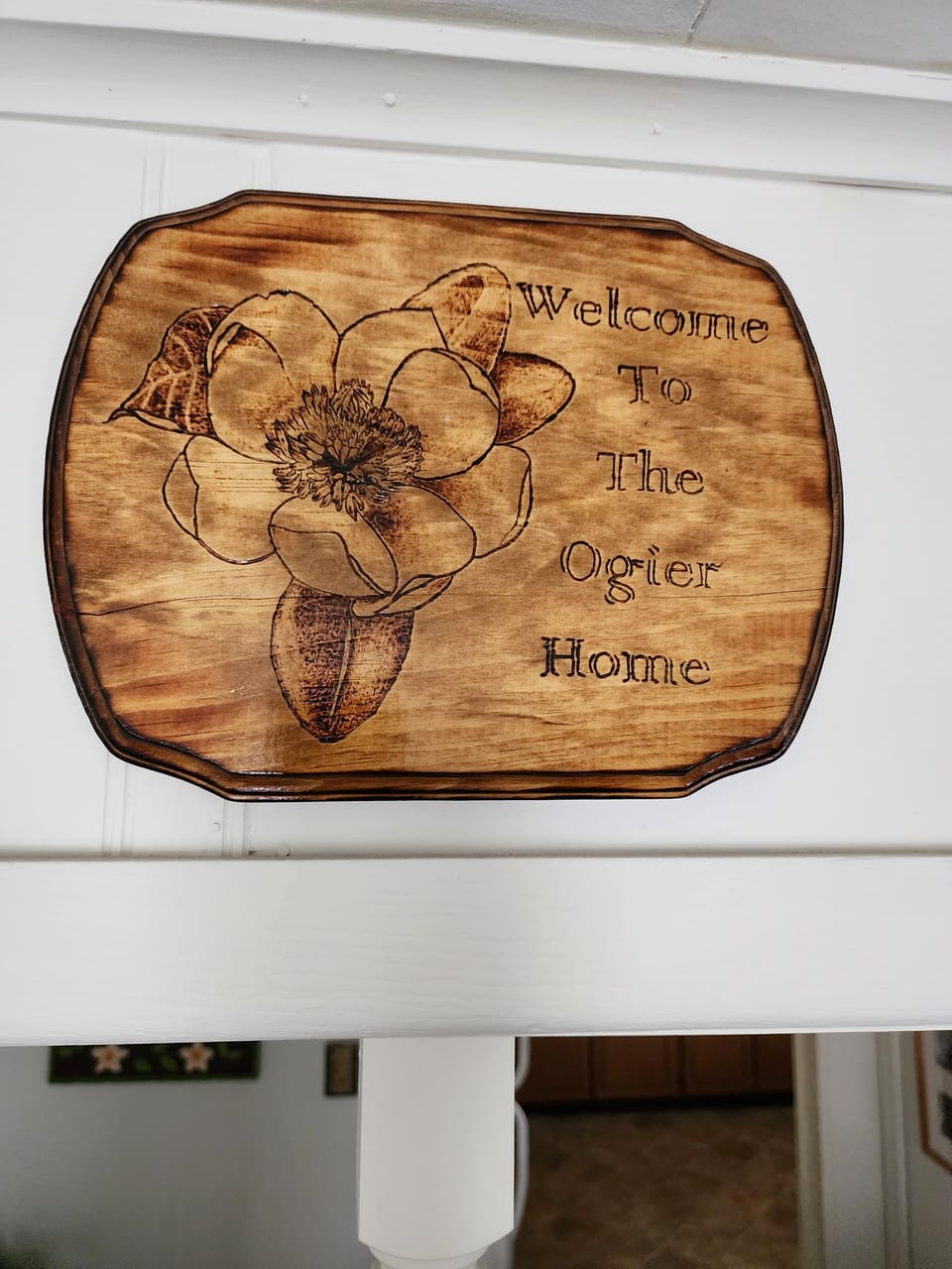 Round wood sign with a hand-burned magnolia and a family welcome message