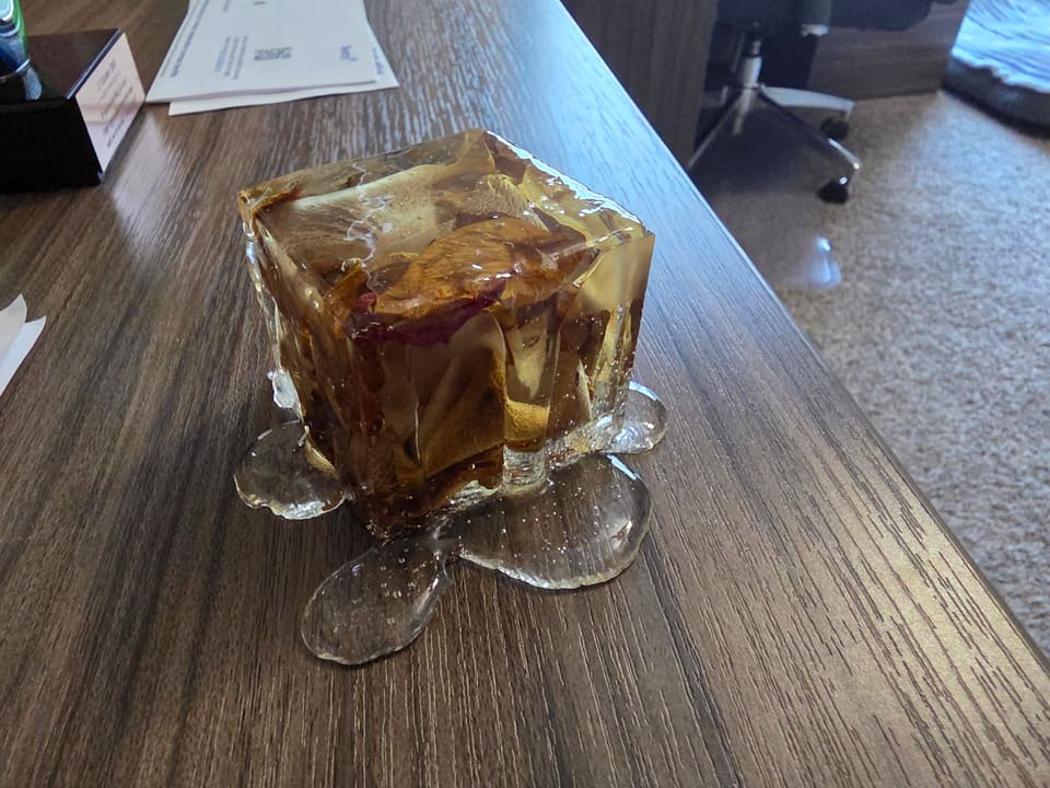 Rose petal resin cube on a wooden desk