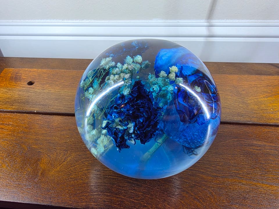 Top view of the resin sphere showing the blue rose and small white flowers