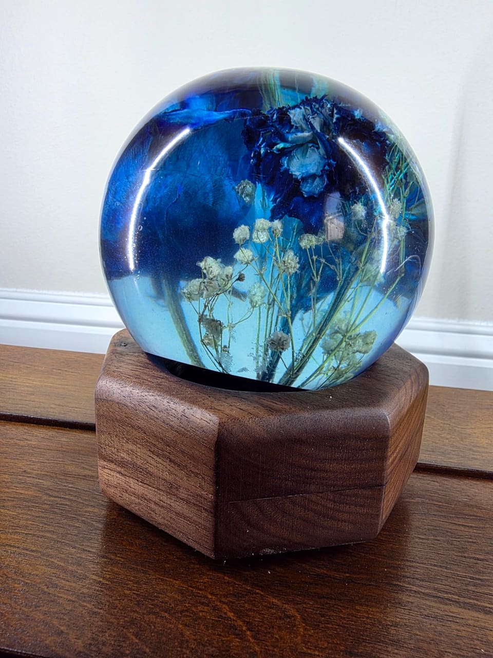 Close view of the blue rose resin sphere seated on its hexagonal walnut base