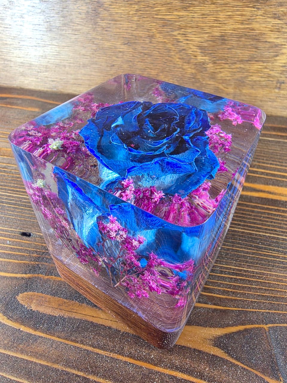 The blue rose resin cube seen from above at an angle, with magenta flowers around the petals