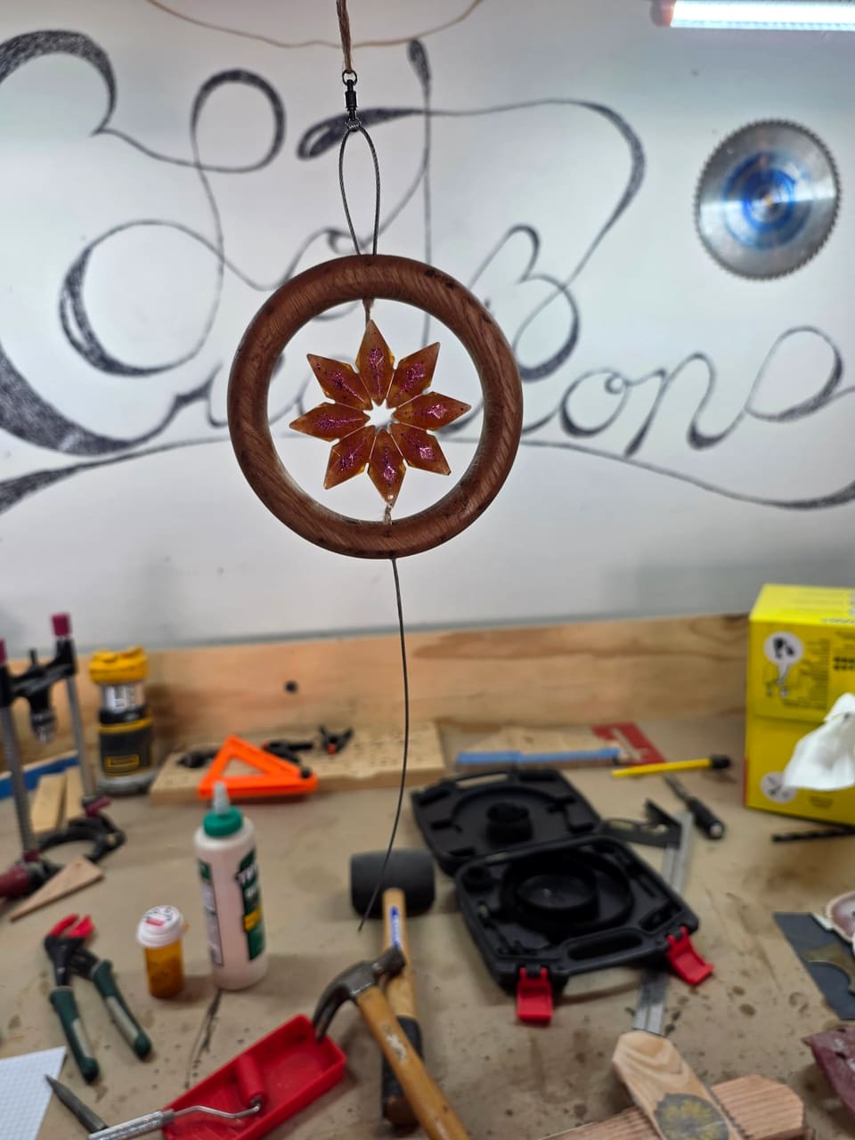 A wooden ring with a carved star-flower in the centre hanging above the workbench