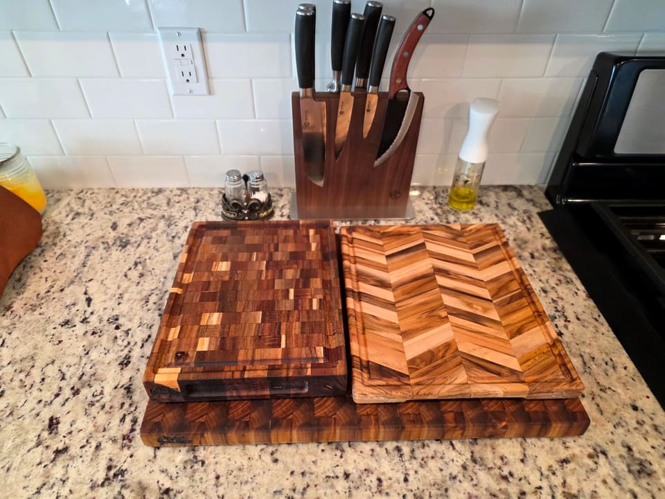 An end-grain cutting board and a herringbone board on a granite counter beside a knife block
