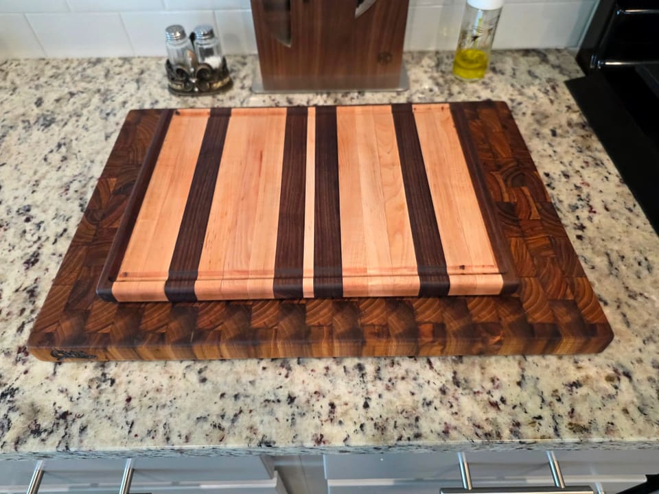 Striped hardwood cutting board with alternating light and dark strips