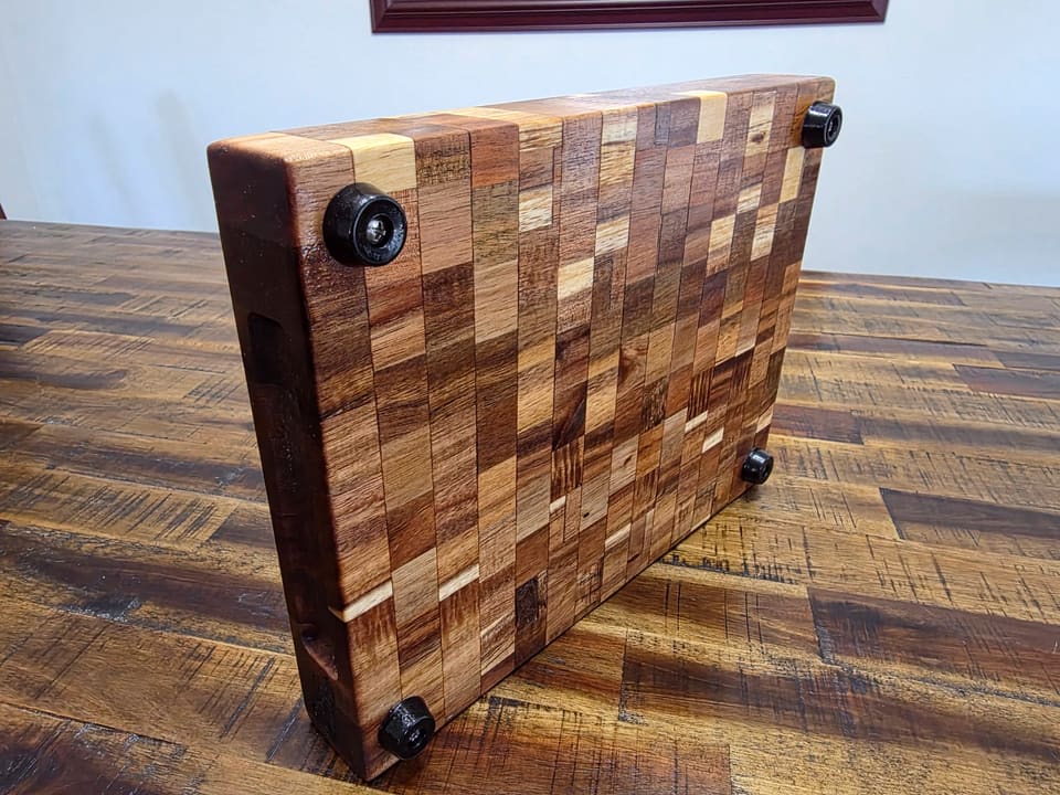 Underside of an end-grain board showing four black rubber feet