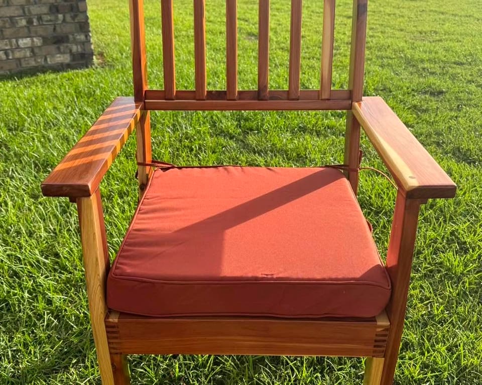 Single slat-back armchair with a rust cushion, shown on grass